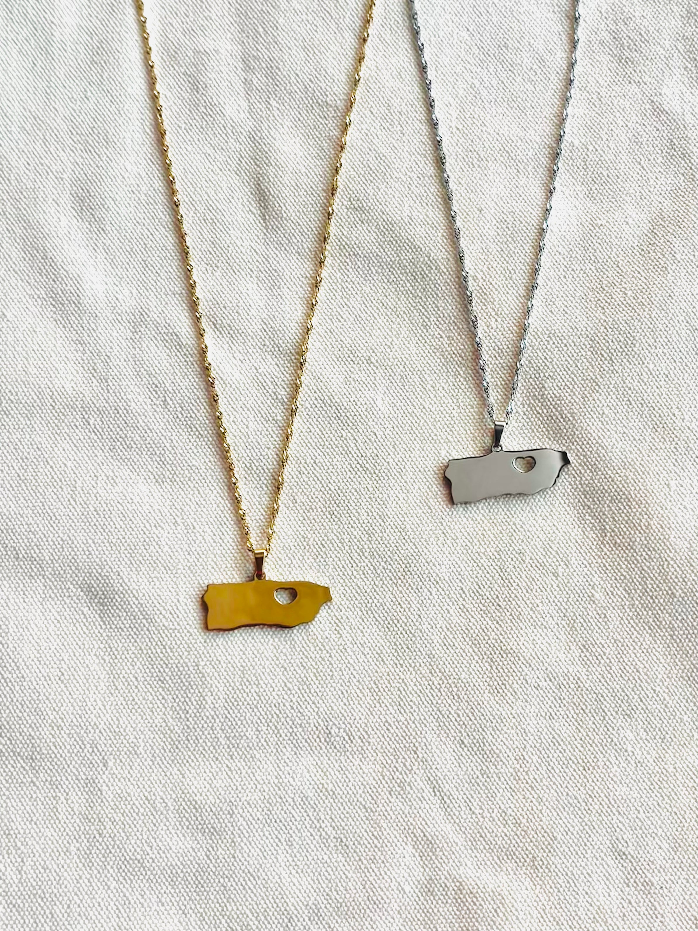 Two necklaces on a light fabric background, one gold and one silver.