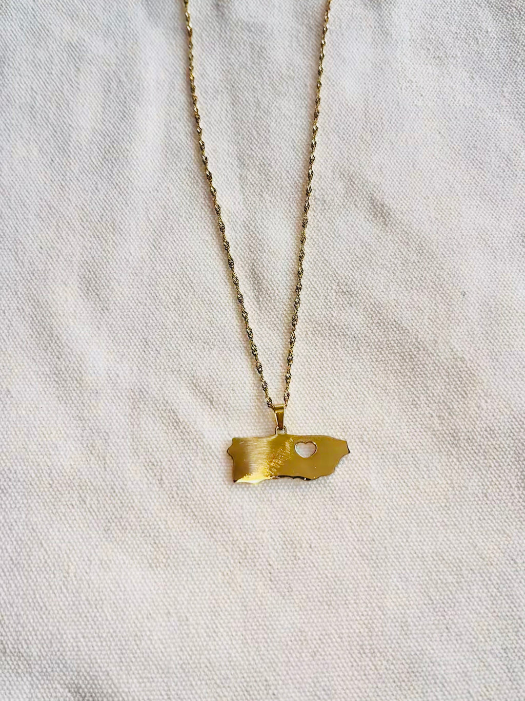 Gold necklace with a pendant on a light gray fabric background