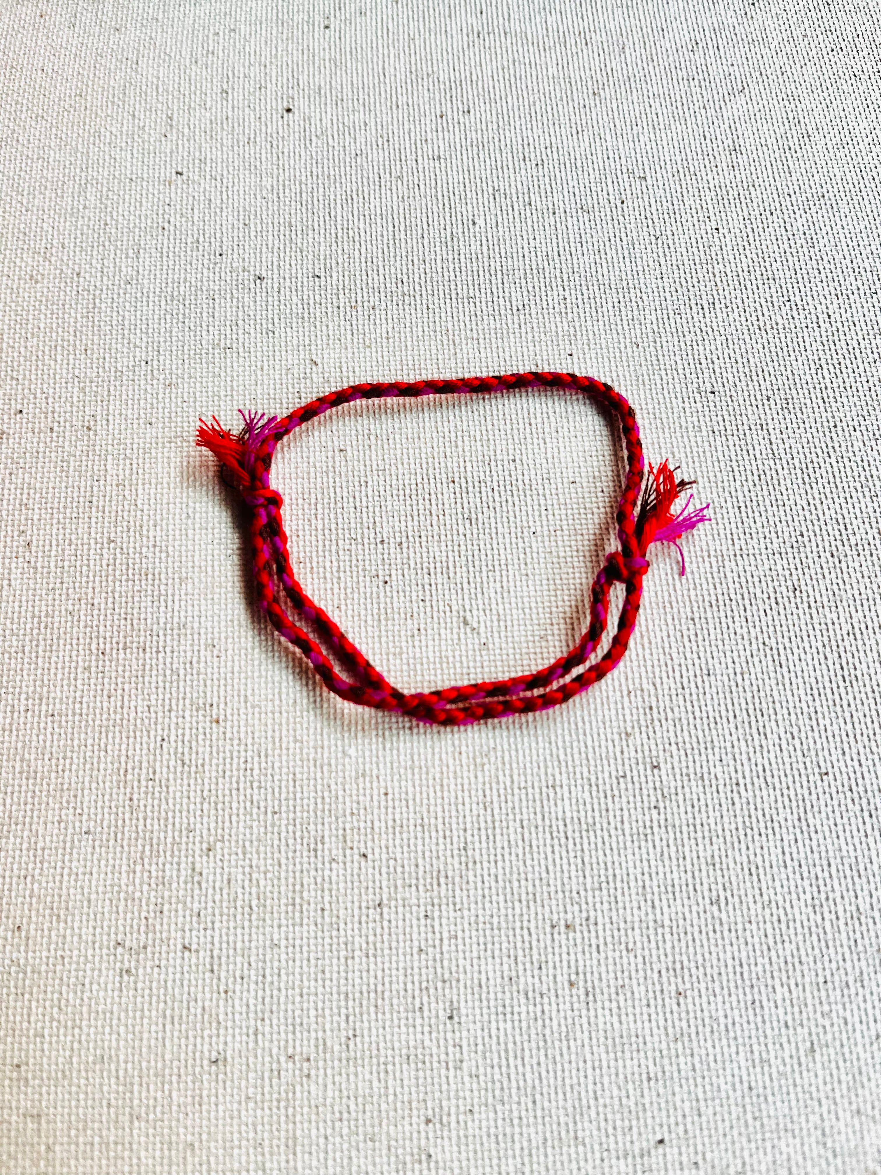 Red braided bracelet on a light gray background