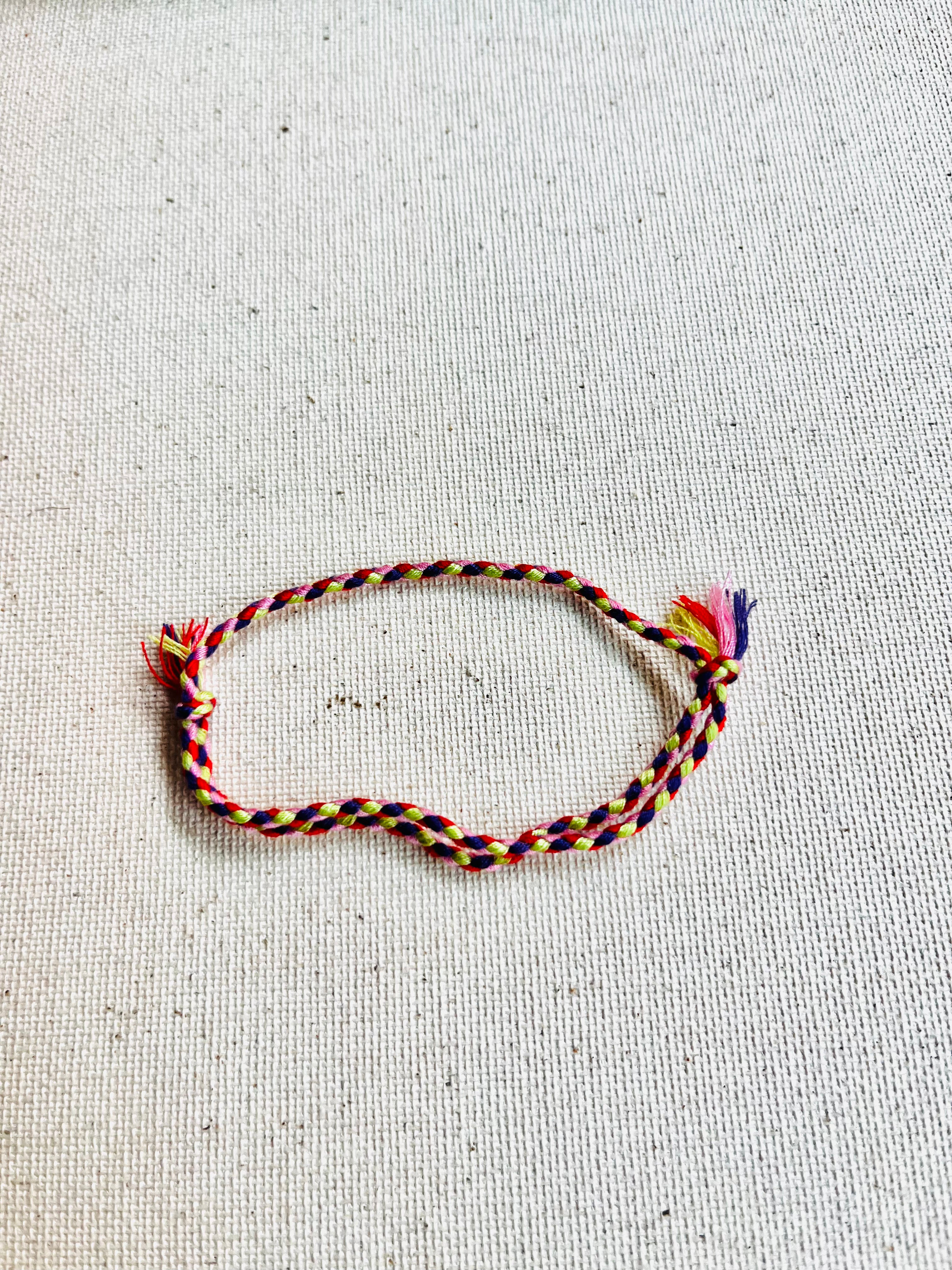 Multicolored braided bracelet on a light gray textured background