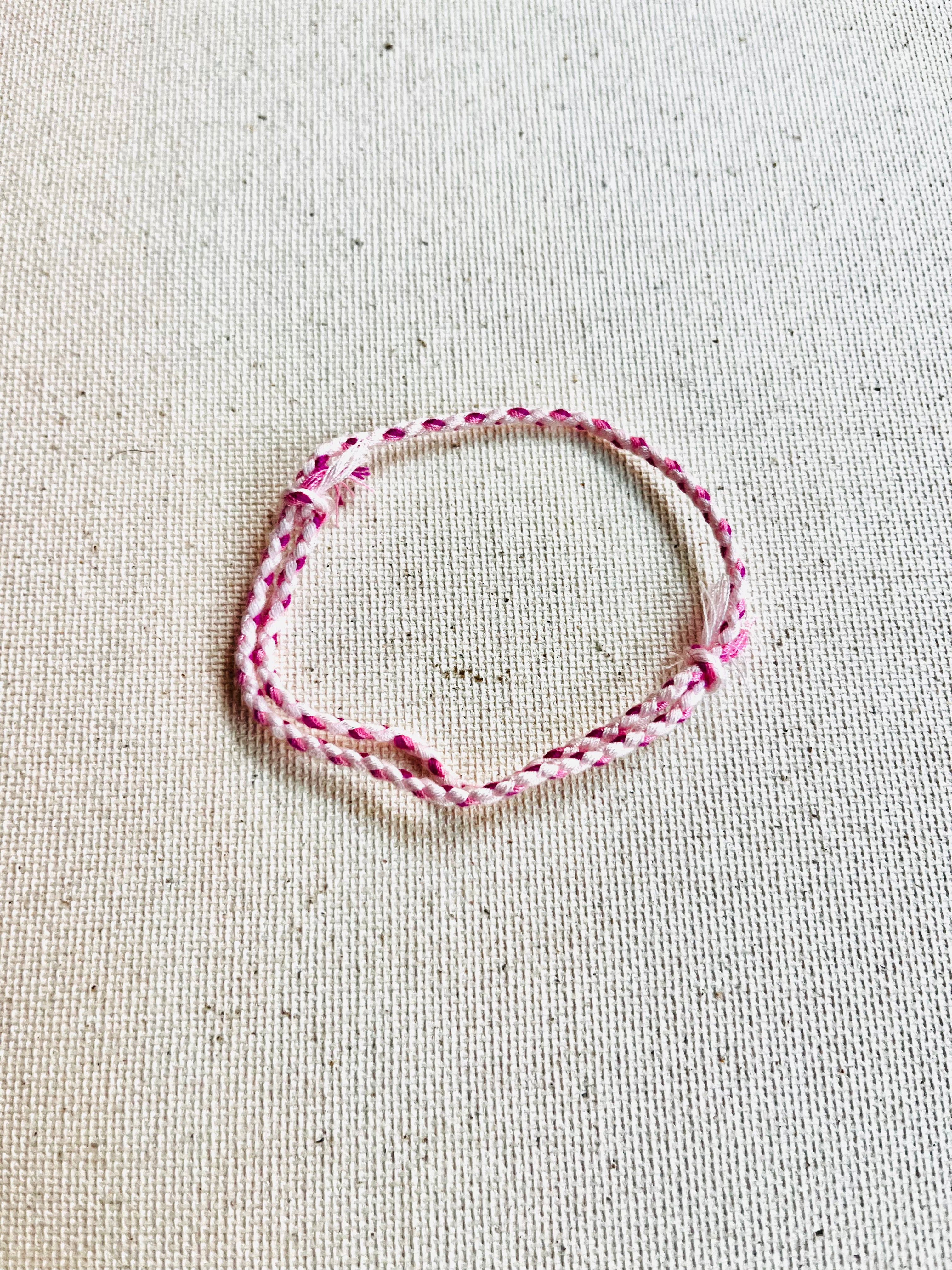 Pink braided bracelet on a textured beige background