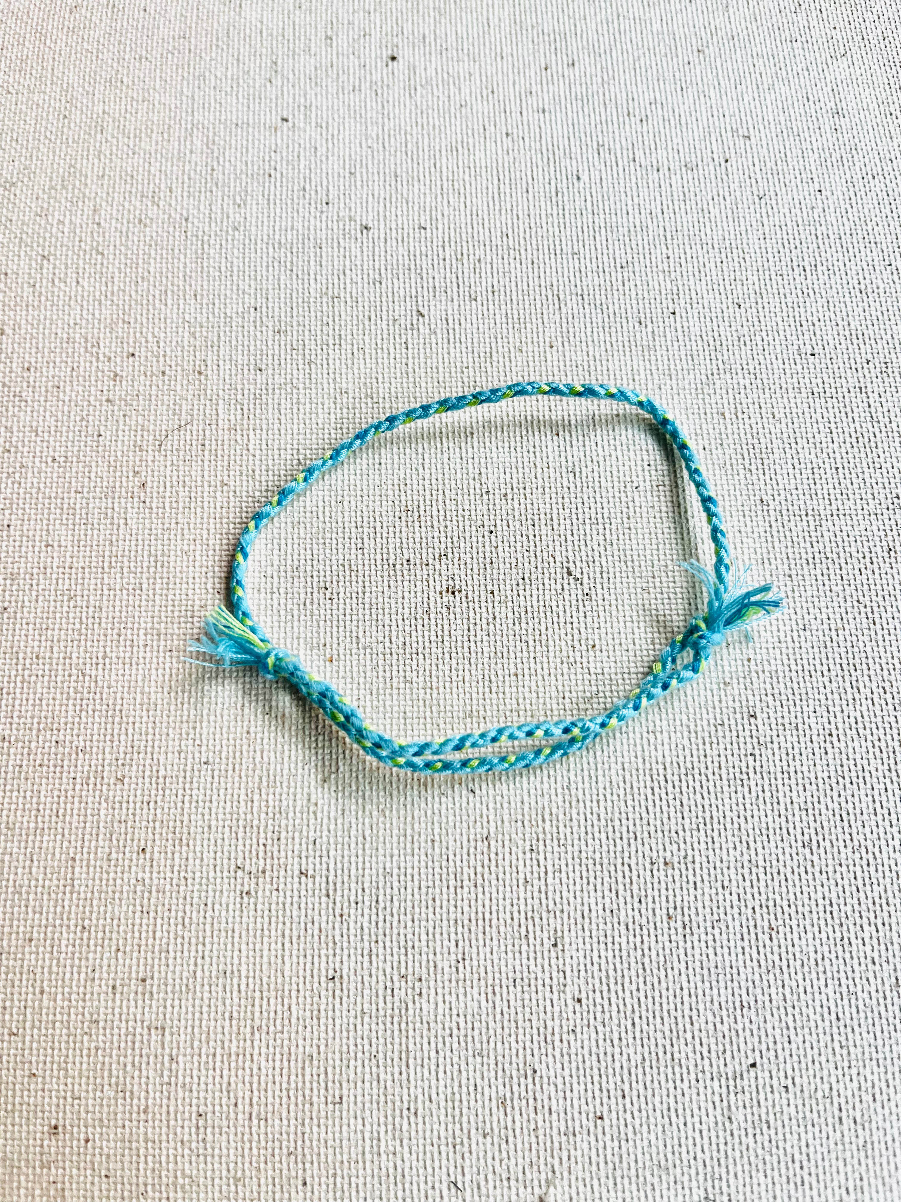 Blue braided bracelet on a textured beige background