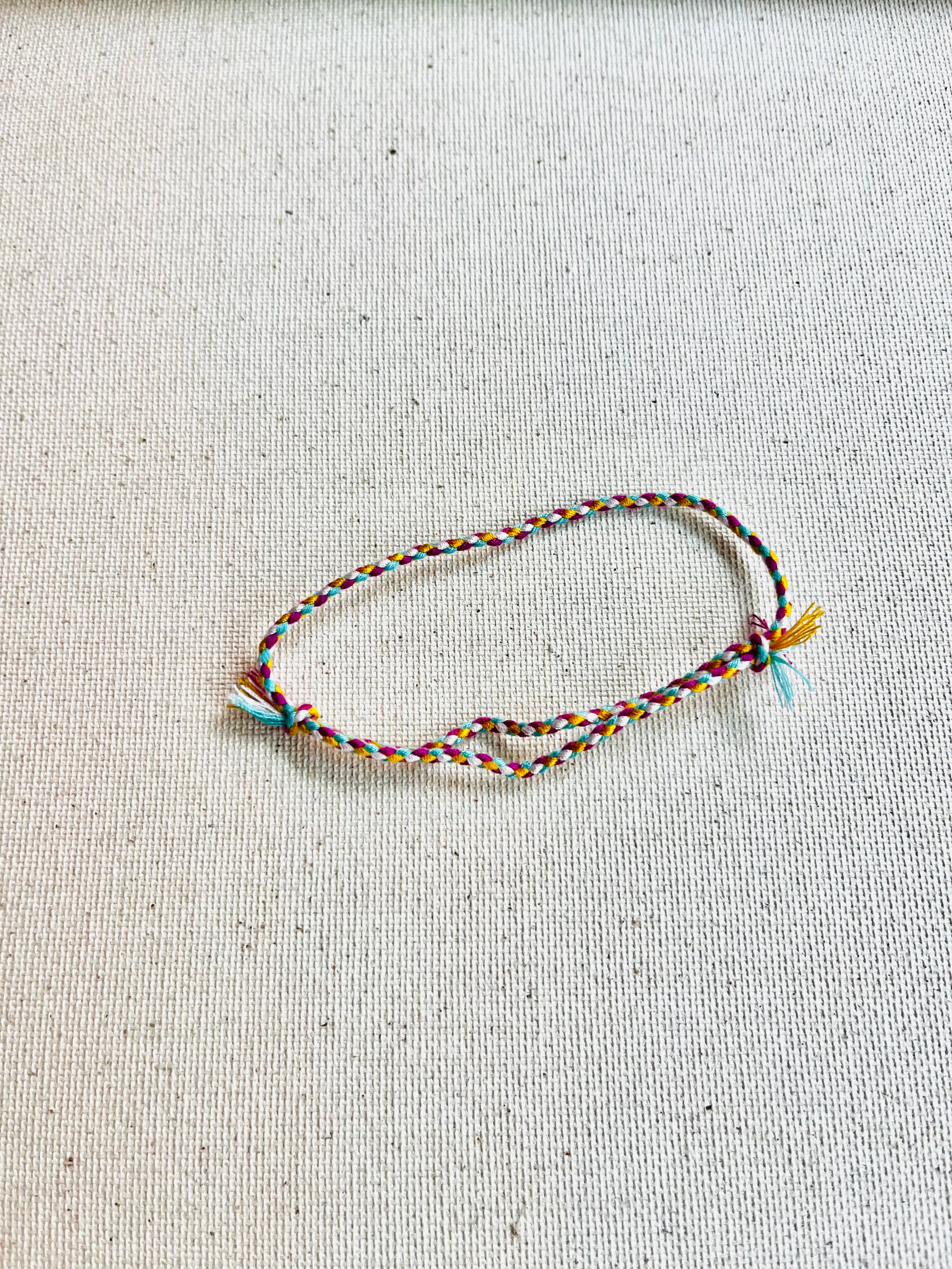 Multicolored braided bracelet on a light gray fabric background