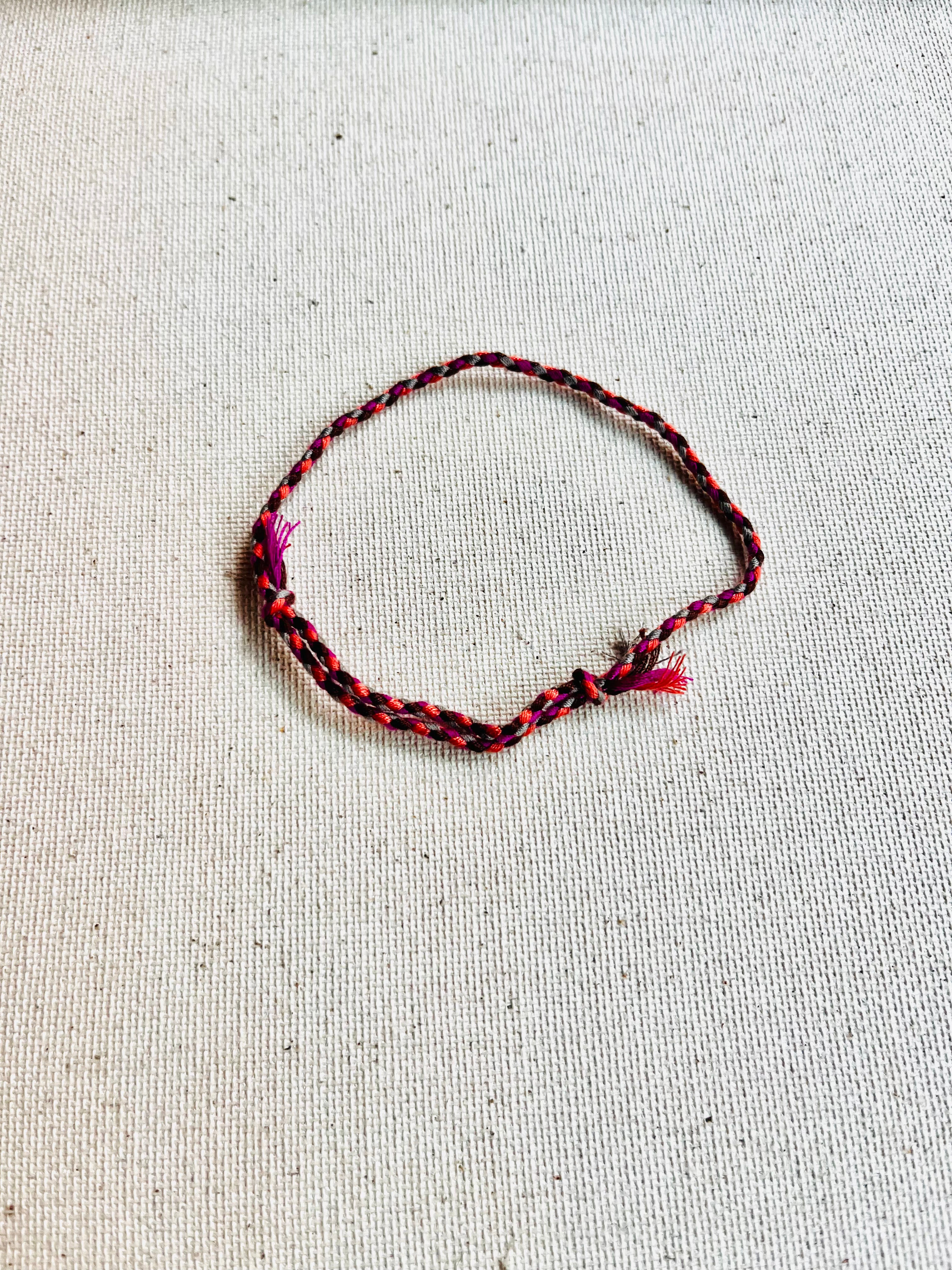 Braided bracelet with red and black pattern on a light gray background