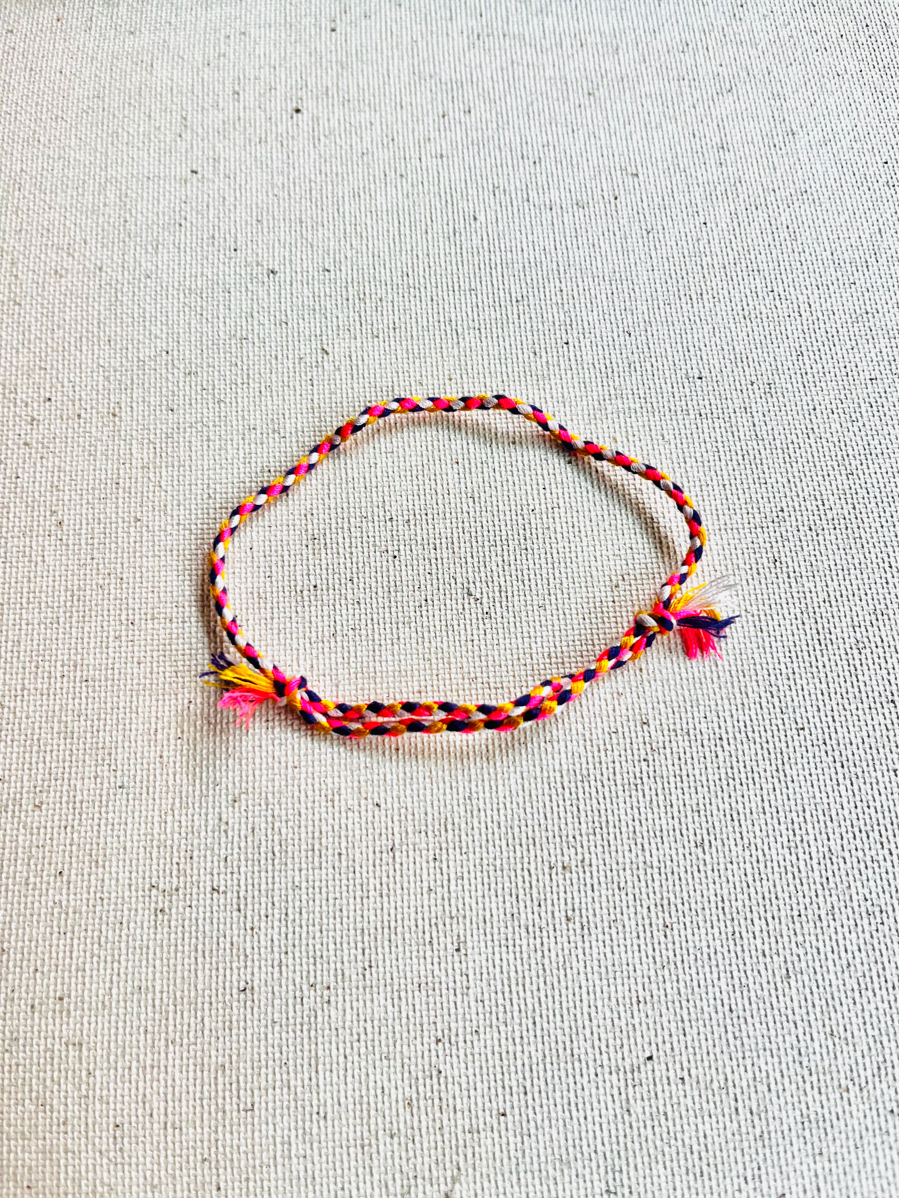 Colorful braided bracelet on a light gray fabric background