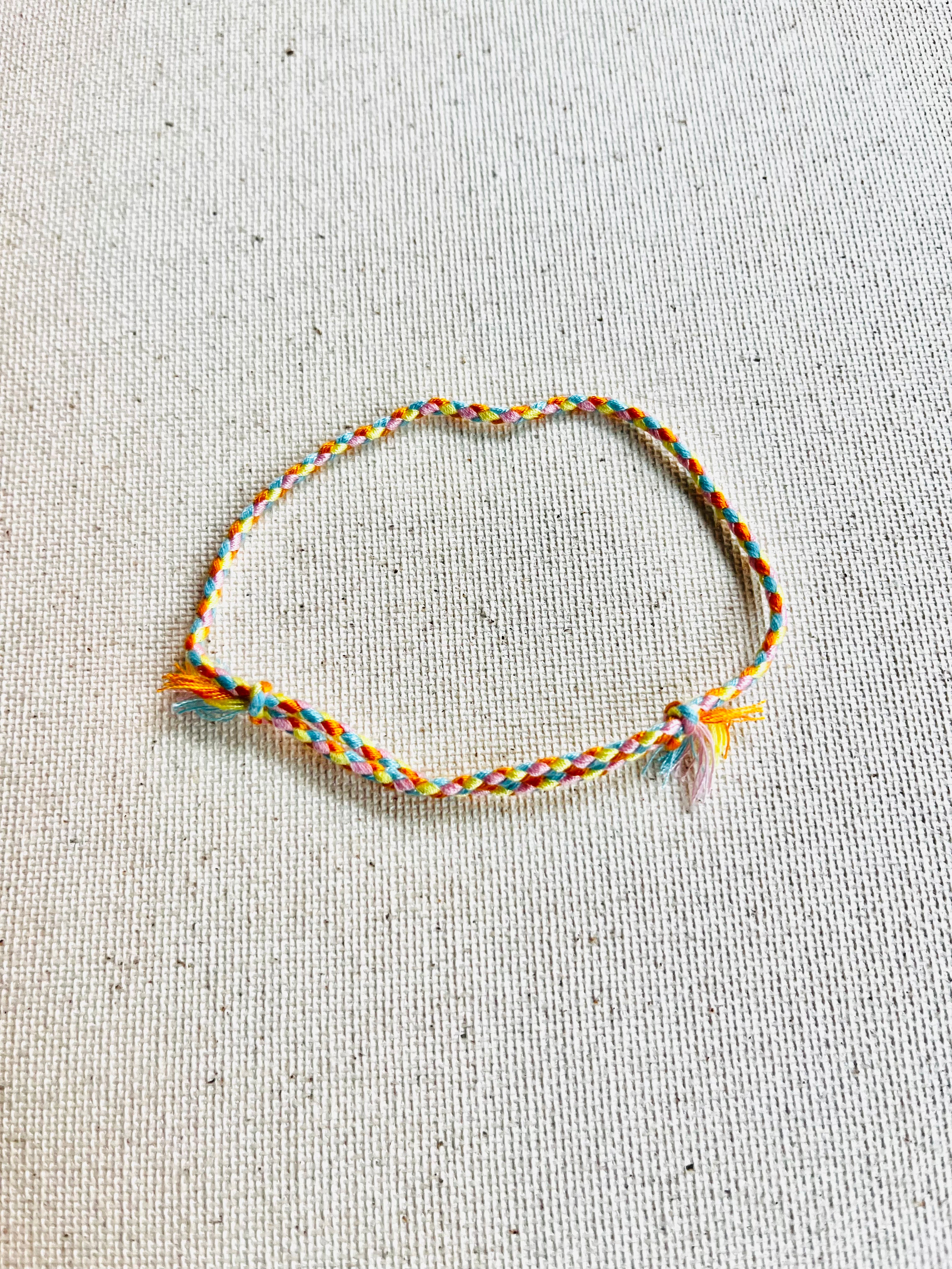 Multicolored braided bracelet on a textured beige background