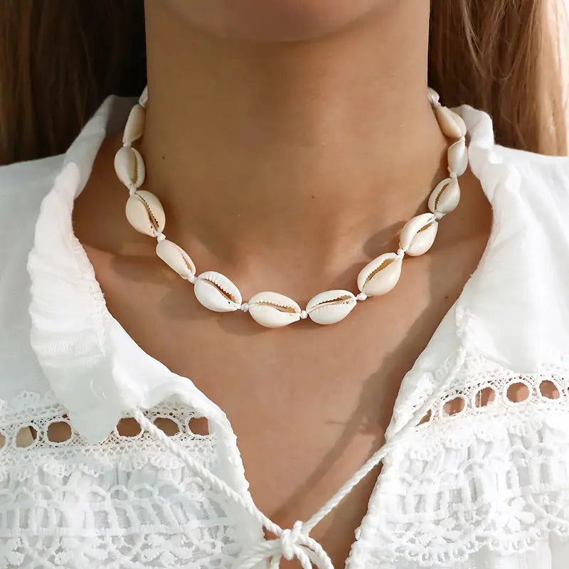 Necklace with shell beads worn by a person in a white top