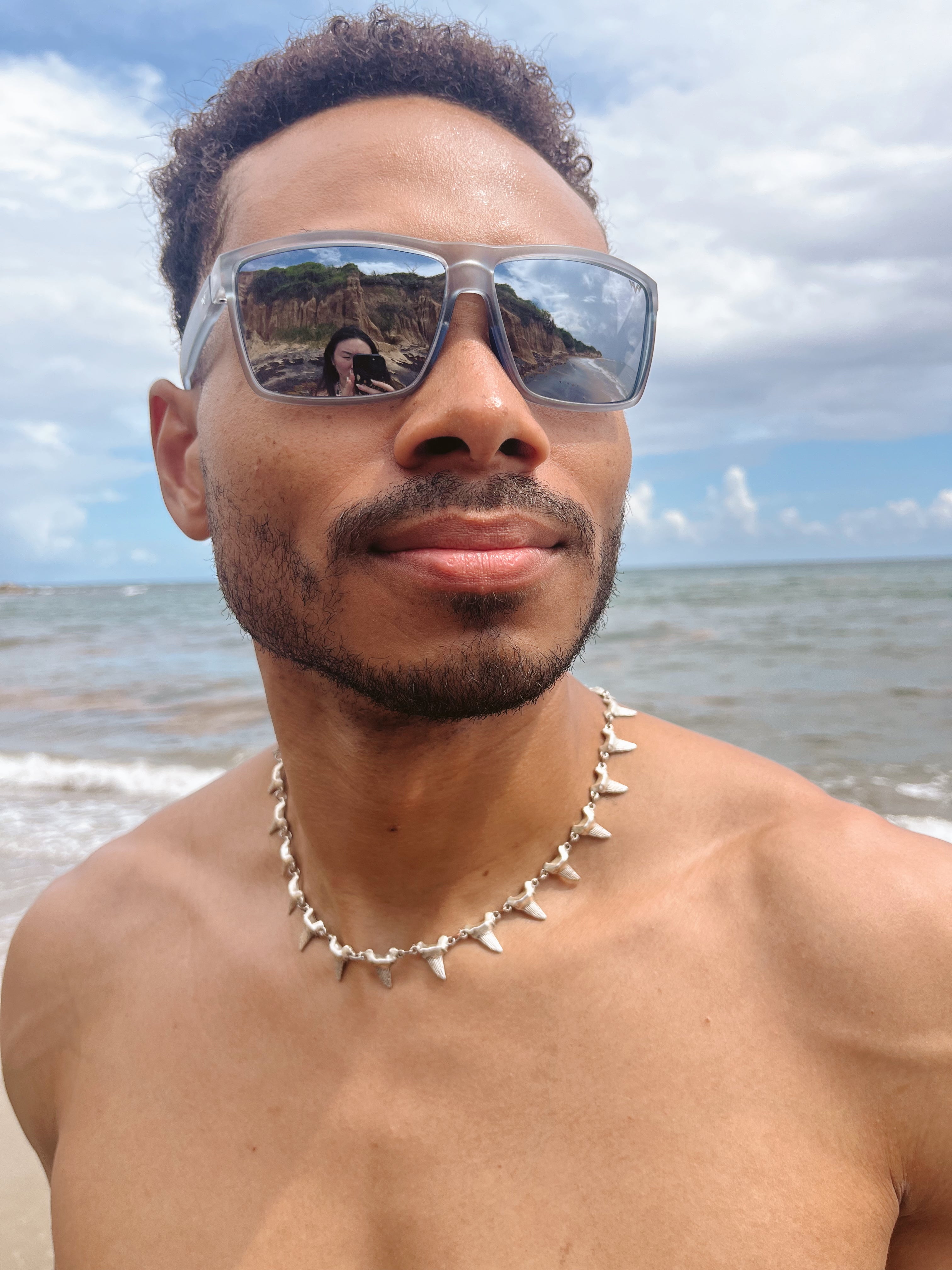 Man wearing sunglasses with a beach and ocean view in the background