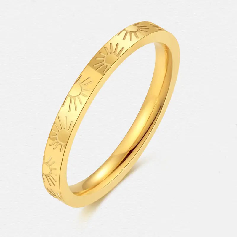 Gold ring with sunburst pattern on a white background