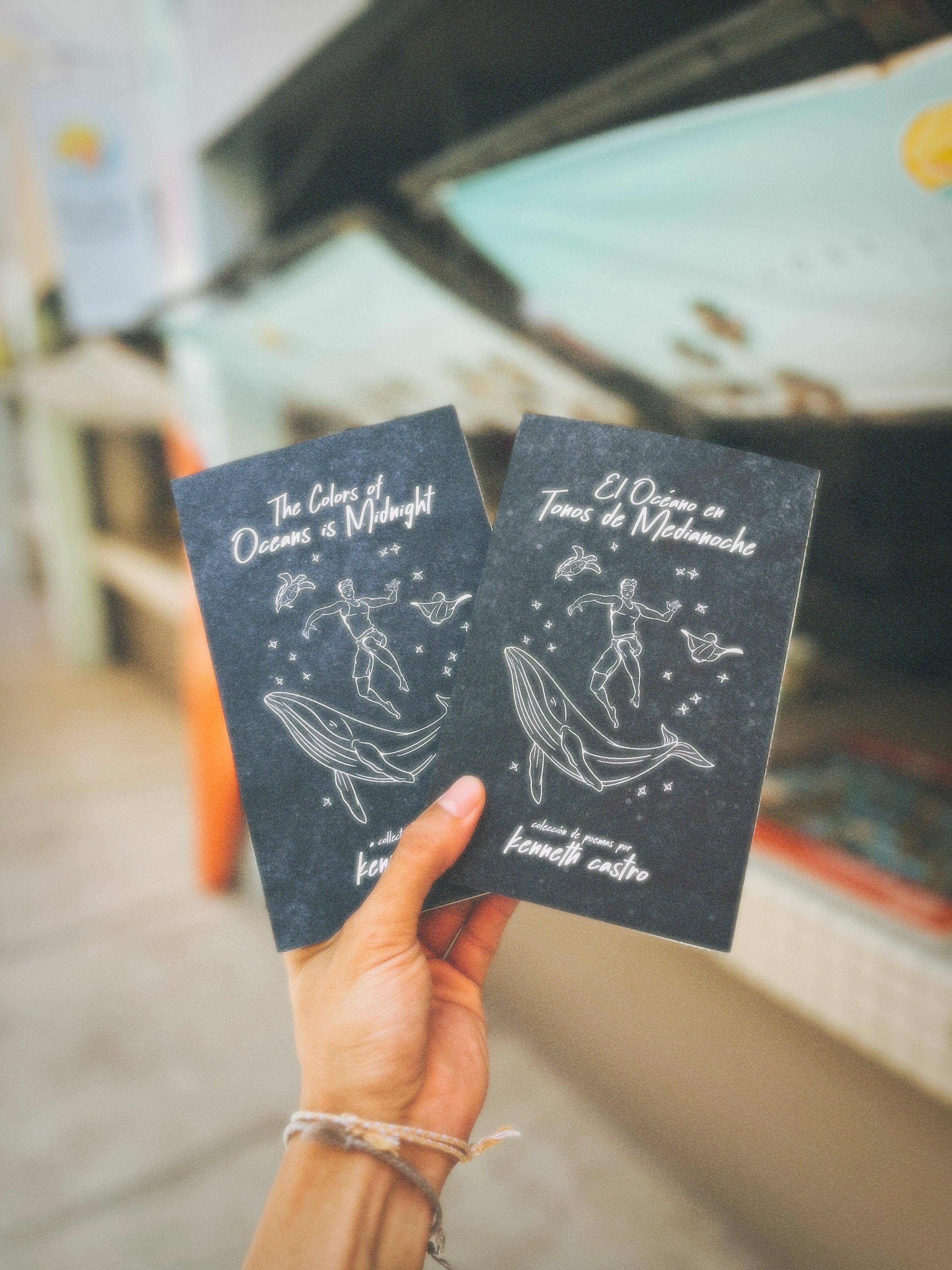 Hand holding two books in front of store 