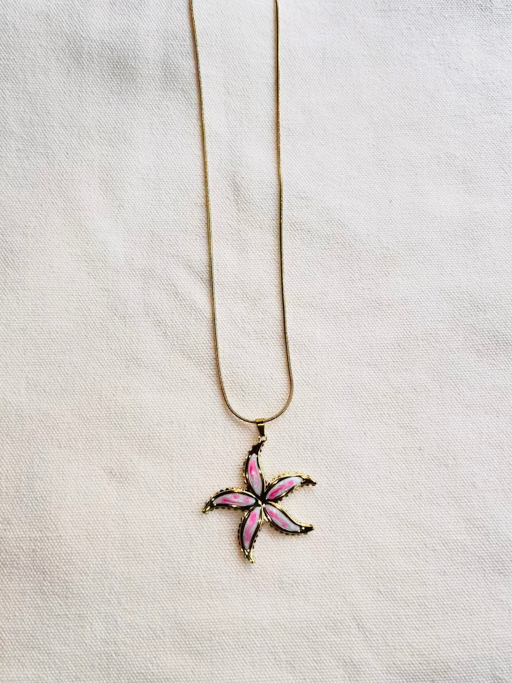 Necklace with a pink flower pendant on a light gray background