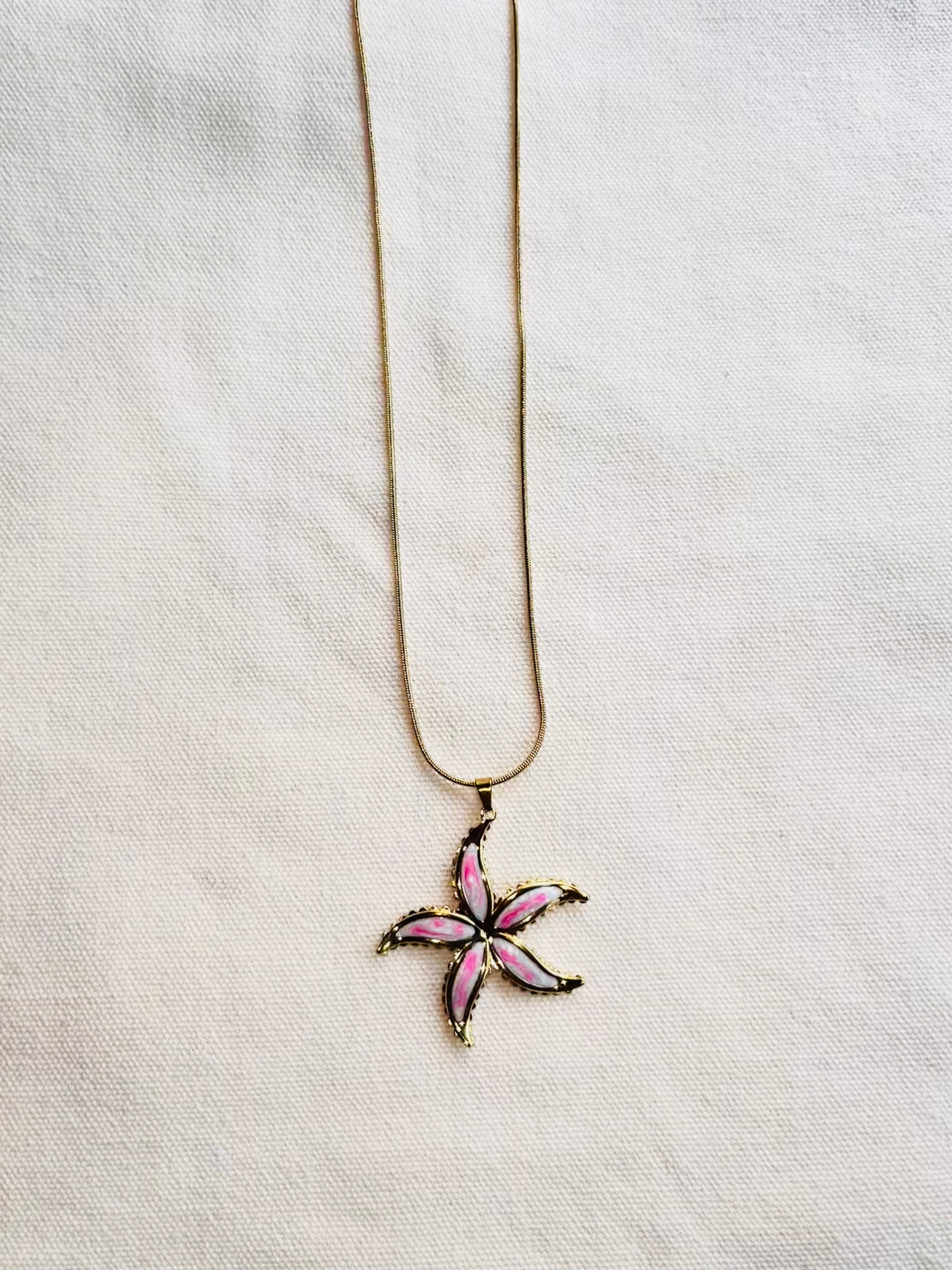 Necklace with a pink flower pendant on a light gray background