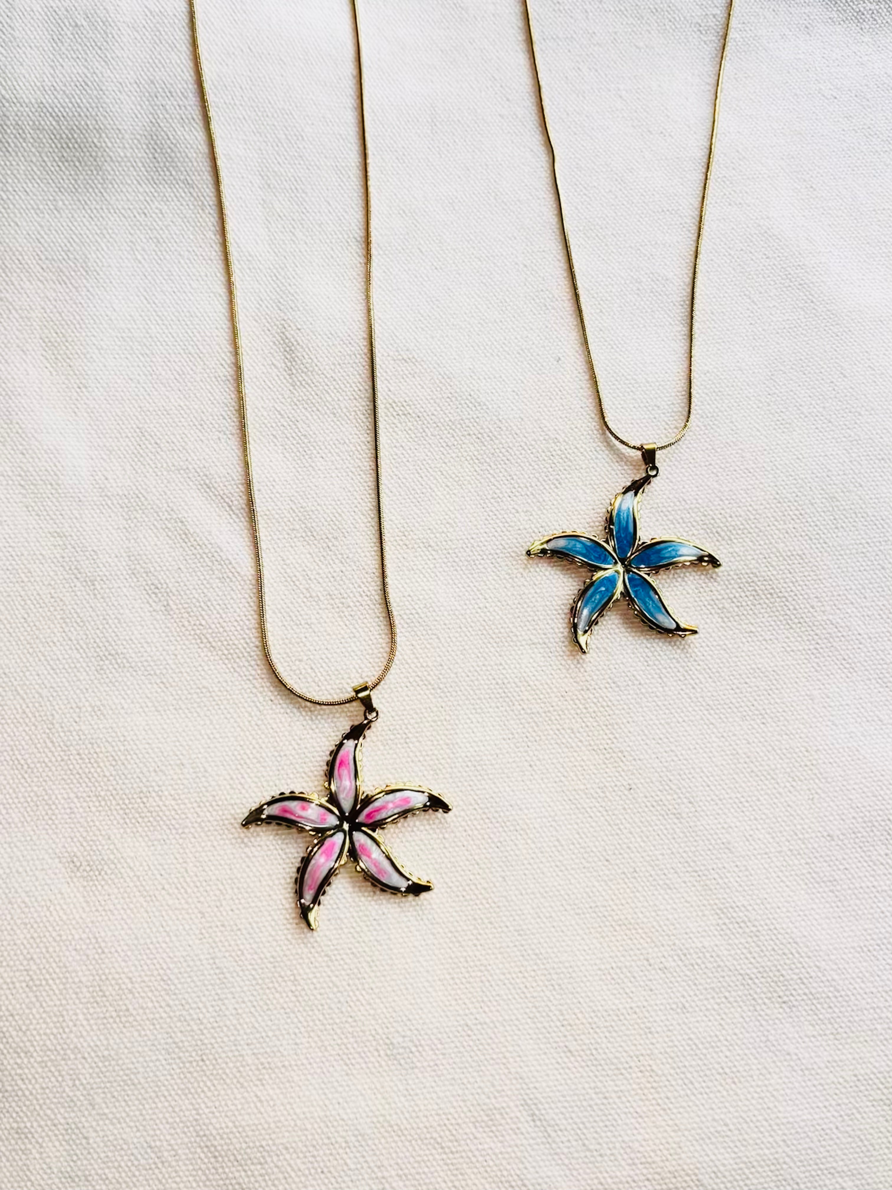 Two star-shaped pendants on necklaces against a white background