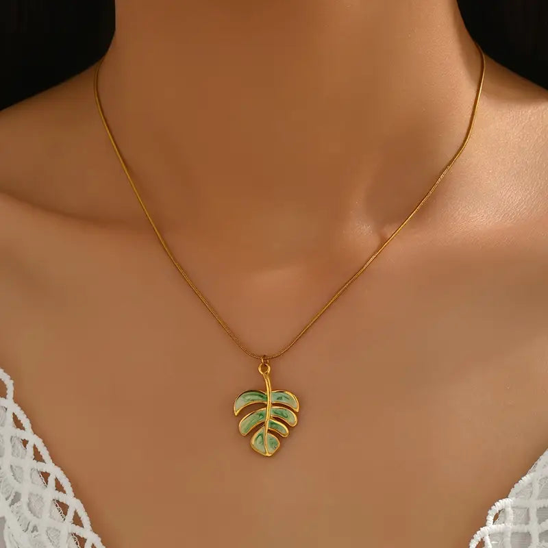 Gold necklace with a leaf pendant on a model wearing a white lace top.